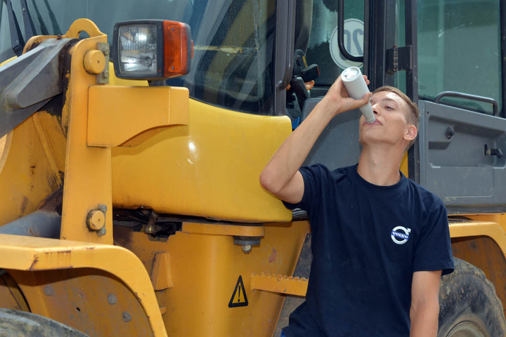 Niklas Kloß (22) trinkt auf einer Baustelle einen Fleisch-Drink in einer Flasche.