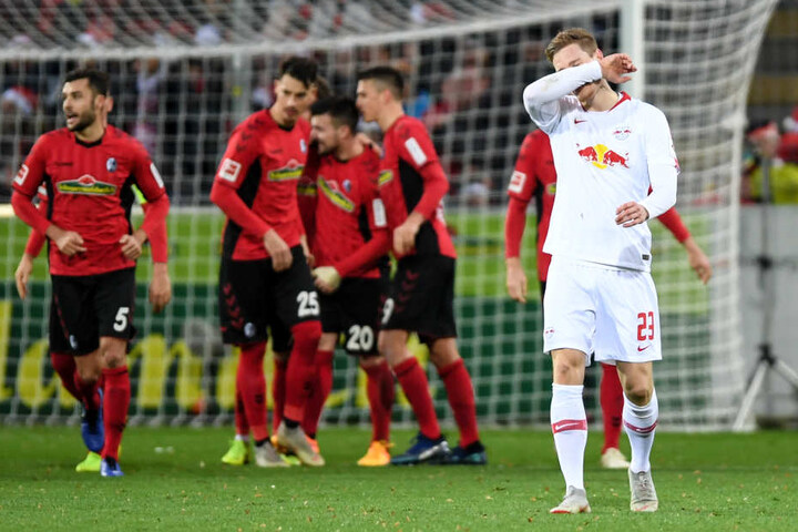 Während sich Linksverteidiger Marcel Halstenberg (r.) enttäuscht mit dem Arm durchs Gesicht fährt, feiern die Freiburger das 2:0 durch Gian-Luca Waldschmidt.