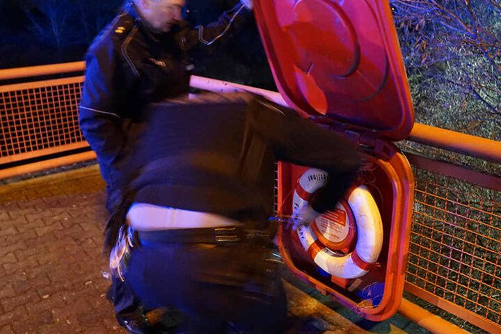 Polizeibeamte bringen den Rettungsring wieder an seinen Platz.