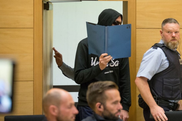 Der Angeklagte betritt einen Sitzungssaal im Landgericht in Begleitung eines Justizbeamten.