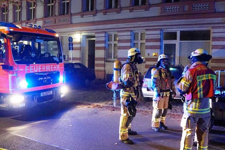 Feuerwehrmänner stehen mit Atemschutzmasken vor dem Haus.