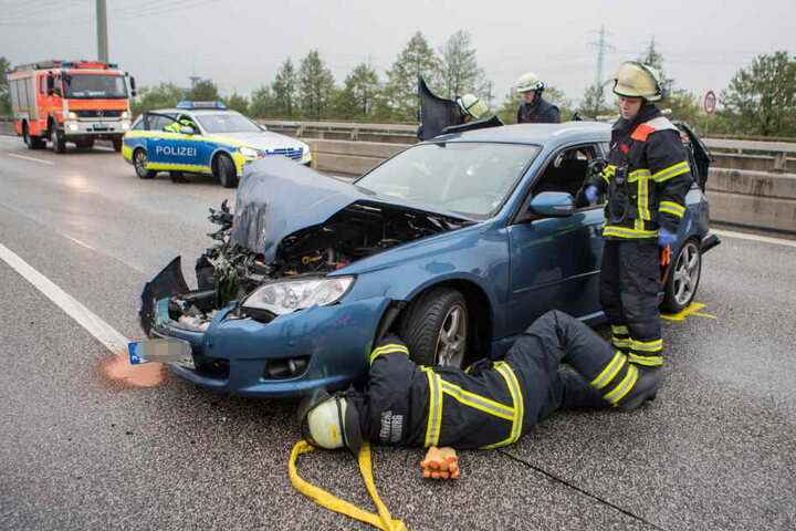 Feuerwehrkräfte untersuchen eines der beteiligten Unfall-Fahrzeuge.
