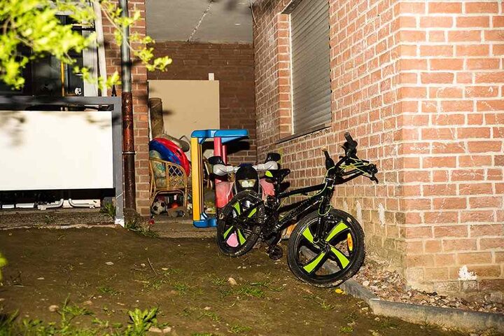 Unter dem Fenster stehen das Fahrrad des toten Jungen und anderes Spielzeug.