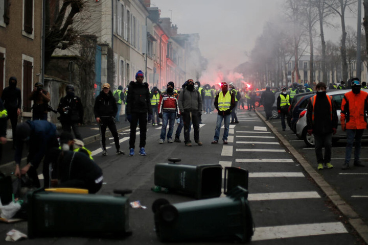 Teilnehmer bei einer Demonstration der "Gelbwesten" stehen in Bourges (Frankreich) auf der Straße und zünden rote Fackeln an.