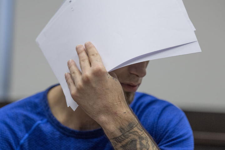 Ali B. verdeckt beim Betreten des Verhandlungssaals sein Gesicht vor den Kameras der Fotografen.