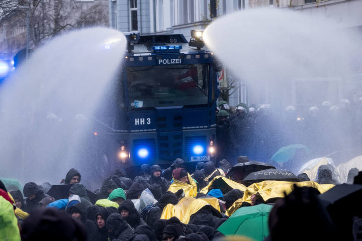 Die Demonstranten versuchen, sich bei der Kälte gegen das Wasser zu schützen.