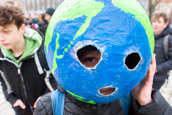 Ein Schüler trägt auf der "Fridays for Future"-Kundgebung eine Weltkugel aus Pappmache auf dem Kopf.