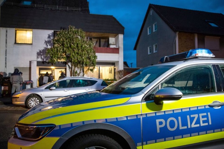 Ein Streifenwagen der Polizei parkt vor einem Mehrfamilienhaus.