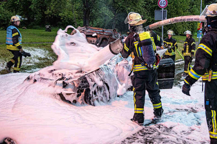 Feuerwehrleute löschen das Auto.