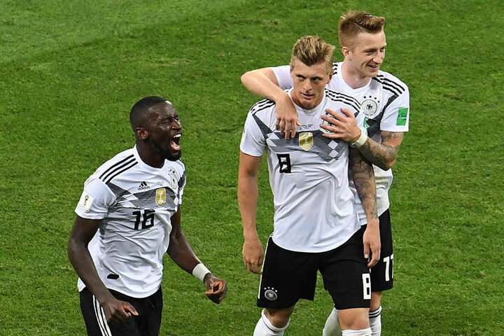 Antonio Rüdiger (l.) brüllt seine Freude heraus und Marco Reus (r.) herzt Torschützen Toni Kroos (M.), der Deutschland in letzter Sekunde zum 2:1-Sieg schoss.