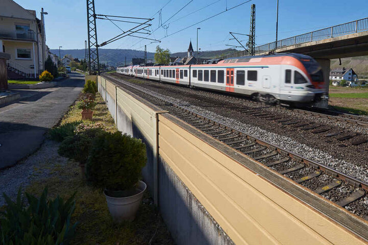 Ein Zug fährt im Rheintal an einer direkt am Gleisbett platzierten niedrigen-Lärmschutzwand vorbei. Die Deutsche Bahn hat im vergangenen Jahr rund 500.000 Euro in Lärmschutzmaßnahmen in Rheinland-Pfalz investiert.