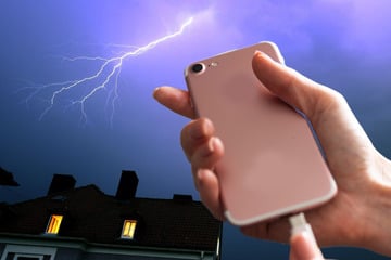 Frau hält Handy beim Laden in der Hand und wird durch Blitzschlag verletzt
