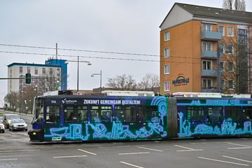 Vater schiebt Kinderwagen über die Straße: Dann kommt eine Tram