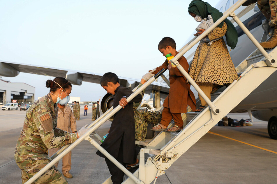 US service members welcome Afghan refugees upon their arrival in Sigonella, Italy.