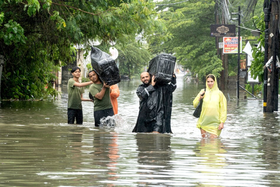 Touristen müssen ihre Koffer durch das Hochwasser tragen.