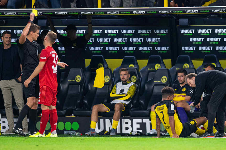 Während Jadon Sancho behandelt wird, bekommt Joshua Kimmich von Schiedsrichter Daniel Siebert den gelben Karton gezeigt bekommt.