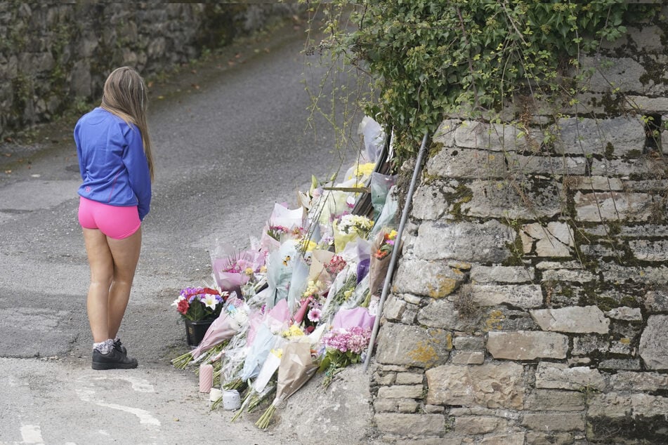 Ein junges Mädchen steht vor der Steinmauer, wo vier junge Menschen am 25. August ums Leben kamen.