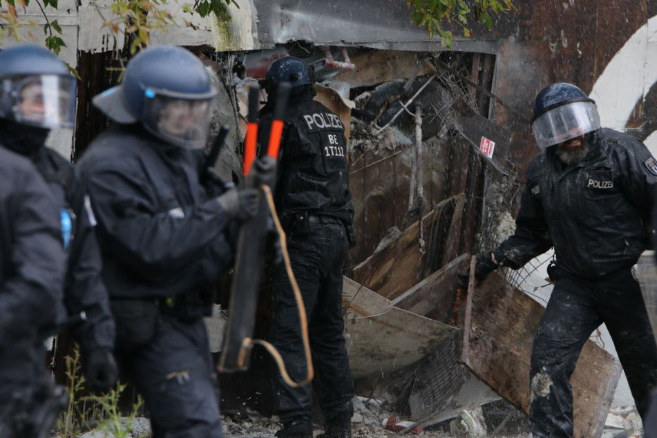 Beamte, die versuchen den Zaun öffnen, werden mit Feuerlöscher besprüht.