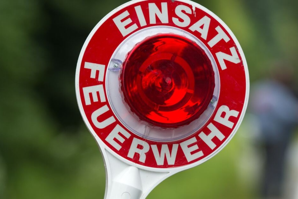 Ein Feuerwehrmann hält eine Kelle mit der Aufschrift "Einsatz Feuerwehr" hoch.