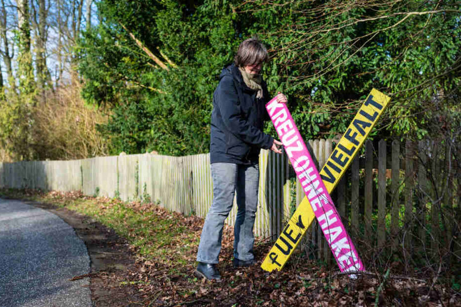Eine Anwohnerin stellt ein Holzkreuz mit der Aufschrift "Kreuz ohne Haken - fuer Vielfalt" in Haarstorf auf.
