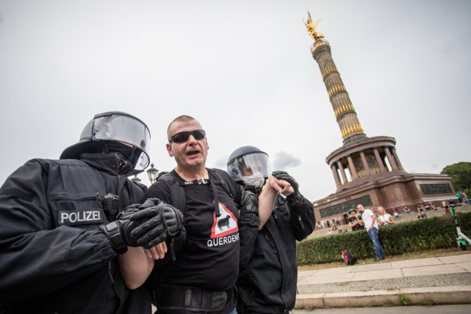 Ein Mann wird bei einem Protest gegen die Corona-Maßnahmen vor der Siegessäule von Polizisten abgeführt.