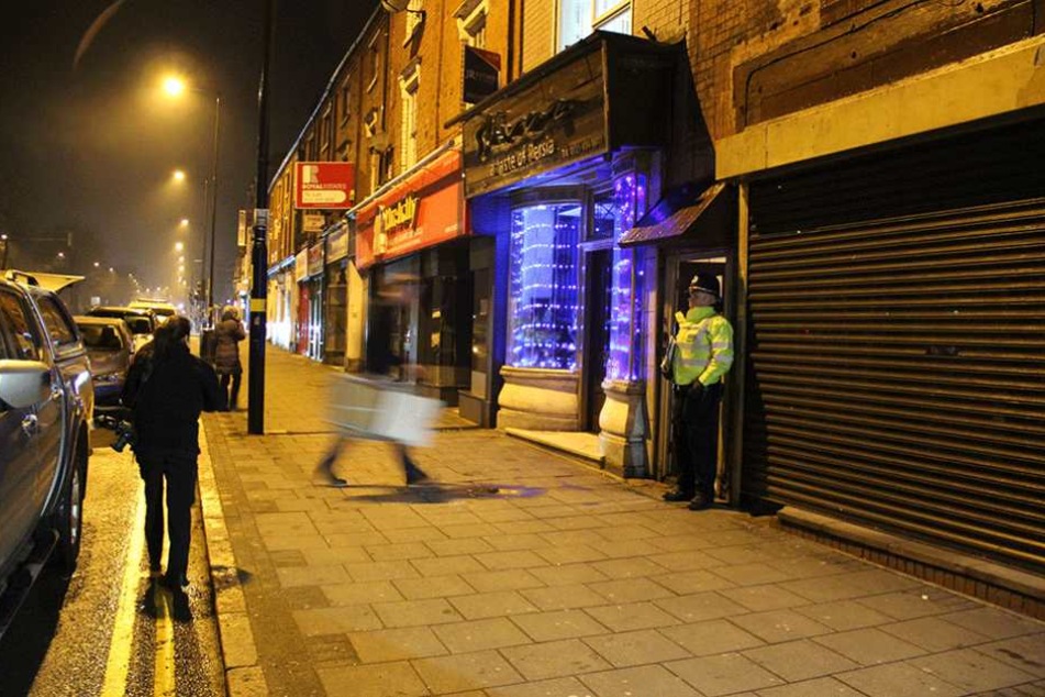 Ein Polizist steht in Birmingham vor einem Wohnhaus. Bewaffnete Polizisten hatten in dem Haus eine Wohnung gestürmt.