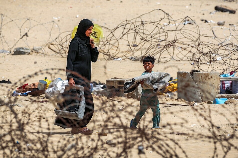 A Palestinian woman and boy walk with belongings past barbed-wire fences as they flee from Rafah in the southern Gaza Strip.