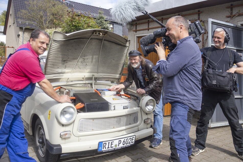 Kfz-Profi Winfried Lupprian und Trabi-Fan Peter Noack zeigen Kameramann Falk Fleischer und Tontechniker Michael Hesse (v.l.), was unter der Trabi-Haube steckt.