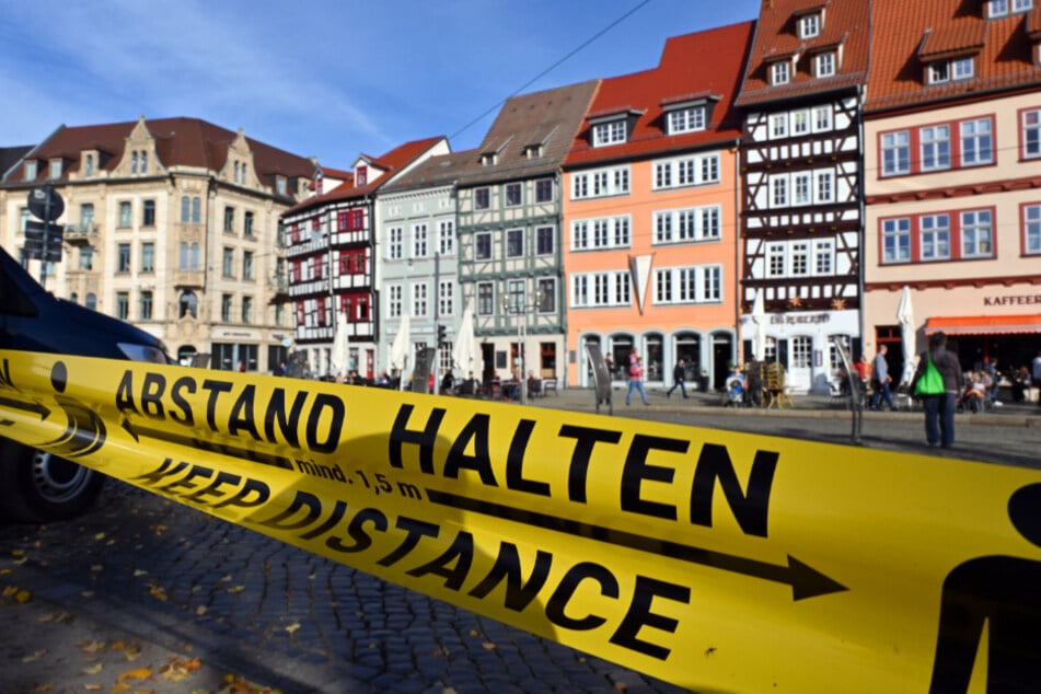 "Abstand halten!" in deutscher und englischer Sprache steht auf einem Flatterband am Domplatz inmitten der Erfurter Altstadt.