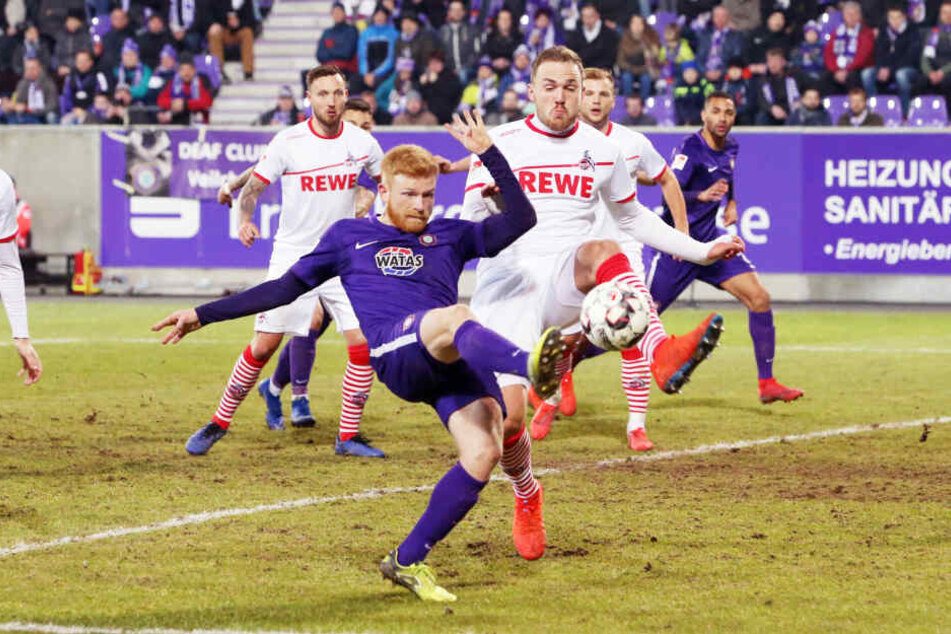 Fabian Kalig (v.) schlägt den Ball vor dem Kölner Rafael Czichos weg. Ende Februar war der Rasen deutlich sichtbar in keinem guten Zustand.