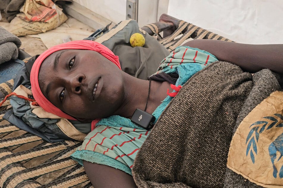 A Sudanese mother who was paralyzed from the waist down during childbirth and had to be carried across the border to flee the RSF attack on Heglig lies on a cot at the Abu al-Naga displacement camp, nearly 500 miles from home, on December 30, 2025.
