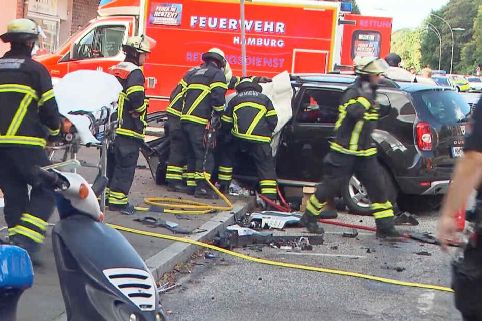Feuerwehrleute versuchen, eingeklemmte Menschen aus dem Auto zu befreien.