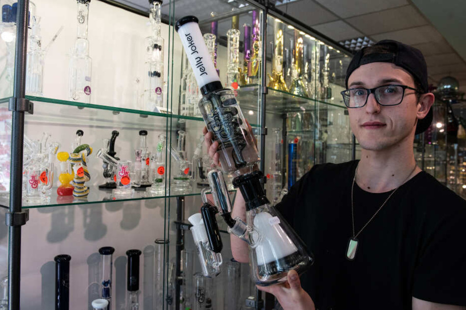 Niklas, Mitarbeiter im Headshop "Jelly Joker", hält eine Wasserpfeife (Bong).
