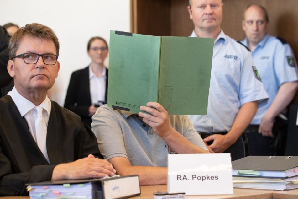 Einer der Angeklagten verbirgt sein Gesicht gegenüber der Presse.