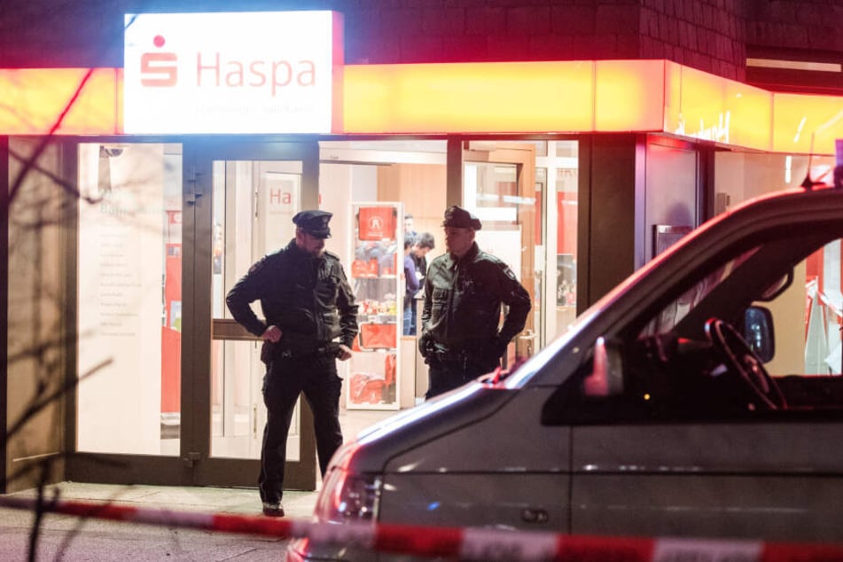 Polizisten stehen im Eingangsbereich der überfallenen Sparkasse.