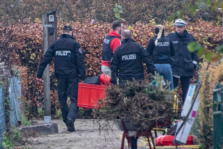 Polizisten durchsuchen die Parzelle einer Kleingartenanlage.