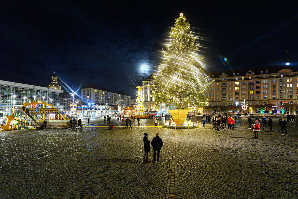 Nur wenige Menschen versammeln sich um einen überdimensionalen Schwibbogen, eine Pyramide und einen Weihnachtsbaum auf dem Dresdner Altmarkt. Der Striezelmarkt fällt dieses Jahr aus.