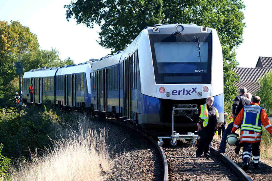 Polizisten und Rettungskräfte der Feuerwehr stehen vor einem verunglückten Zug auf dem Bahngleis bei Isenbüttel.