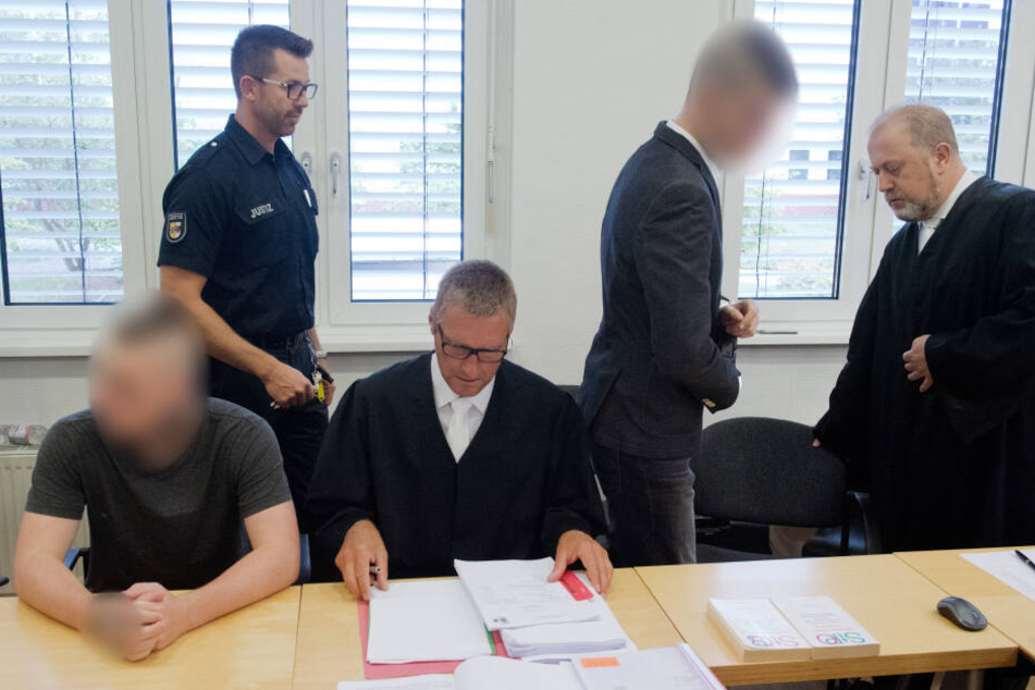 Der 19-jährige Angeklagte (l.) und der 21-jährige Angeklagte (4.v.l.) warten im Gerichtssaal im Landgericht neben ihren Anwälten auf dem Beginn des Prozess.