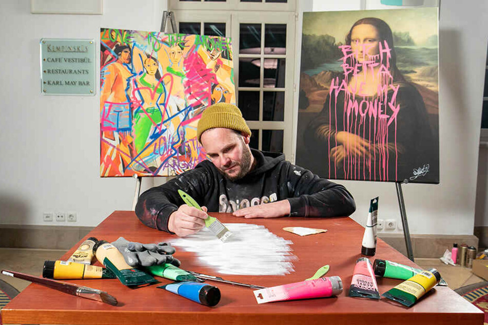 René Turrek legt in der Mitte der Tischplatte das "Gesicht" mit Acrylfarben an.