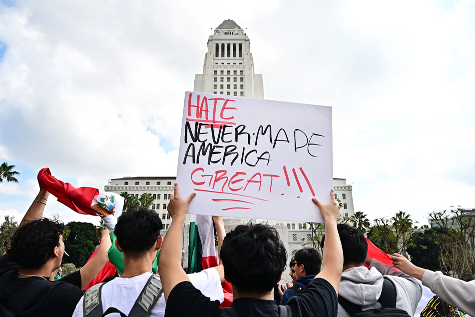 Protesters raise a sign reading "Hate Never Made America Great" in front of Los Angeles City Hall.