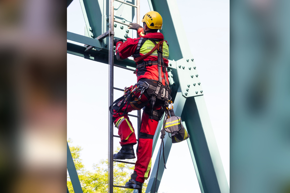 Ein Höhenretter erklimmt den Mast, um zu der feststeckenden Gondel zu gelangen.