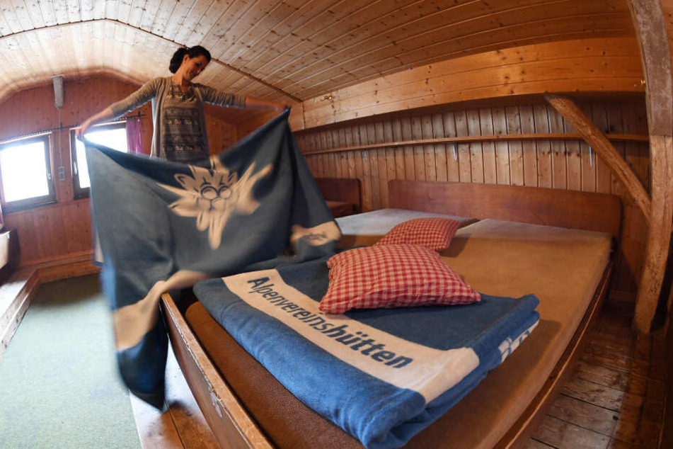 Hüttenpersonal legt die neuen hellblauen DAV Decken in einem Lager auf dem Kreuzeckhaus im Wettersteingebirge zusammen.