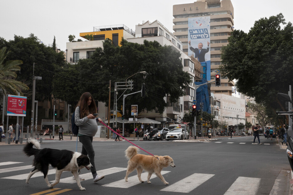 Tel Aviv: Eine Passantin geht mit Hunden an einer Gebäudewand vorbei.