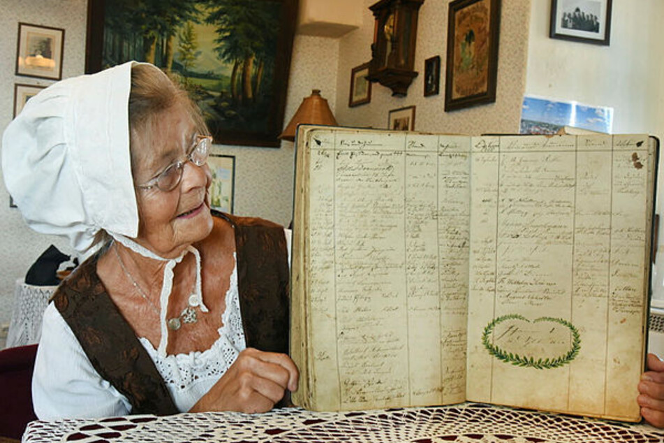 Die ehrenamtliche Türmerin Dolma Hummel (73) vom Verein "Rettet St. Aegidien" hält ein Gästebuch der Türmerfamilie aus dem Jahr 1860 in den Händen.
