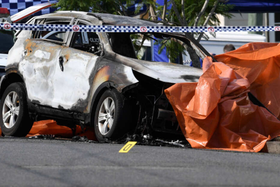 Das Auto der Familie ist völlig ausgebrannt und mit einer orangenen Plane bedeckt.