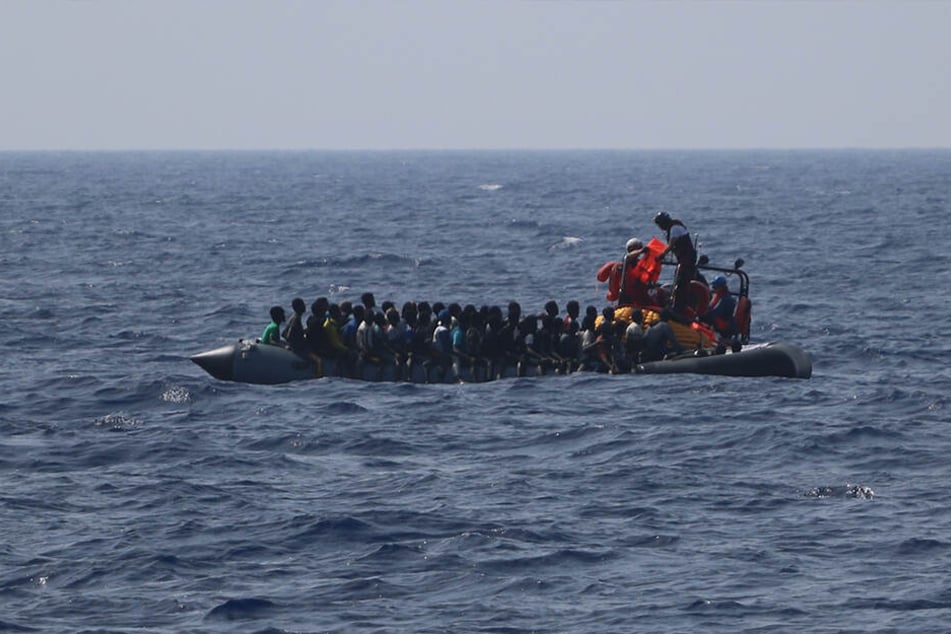 Ein Team der Hilfsorganisation SOS Mediterranee verteilt Rettungswesten auf einem in Not geratenen, im Mittelmeer treibenden Schlauchboot.