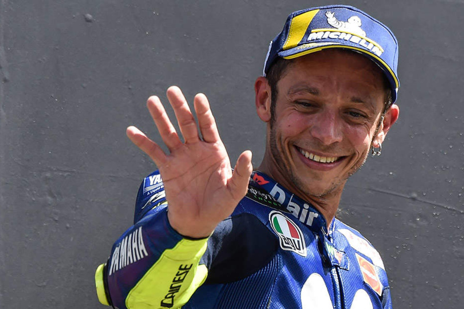 Freudig lächelnd winkt Valntino Rossi vom Siegerpodest.