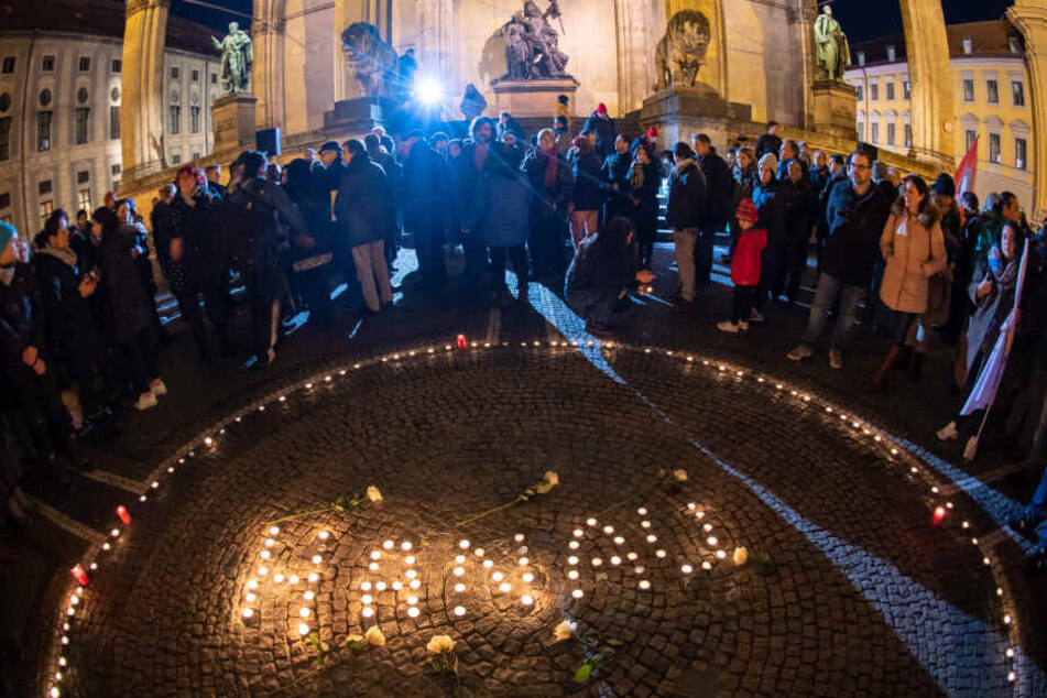 Passanten halten in der Innenstadt mit Kerzen eine Mahnwache für die Opfer von Hanau ab.