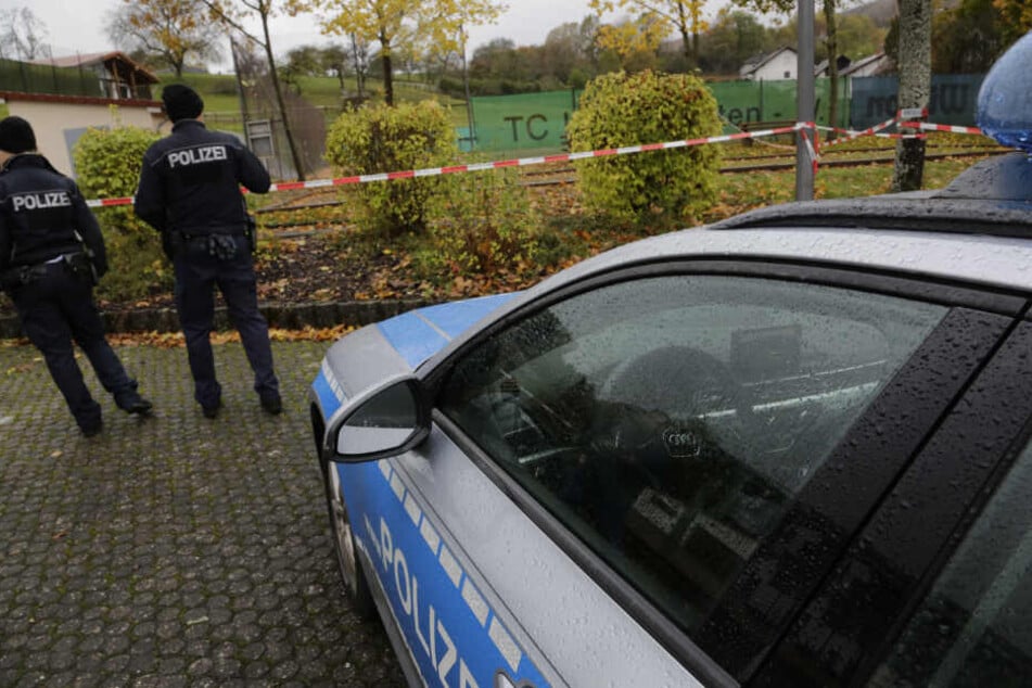 Polizisten stehen vor einem Flatterband.